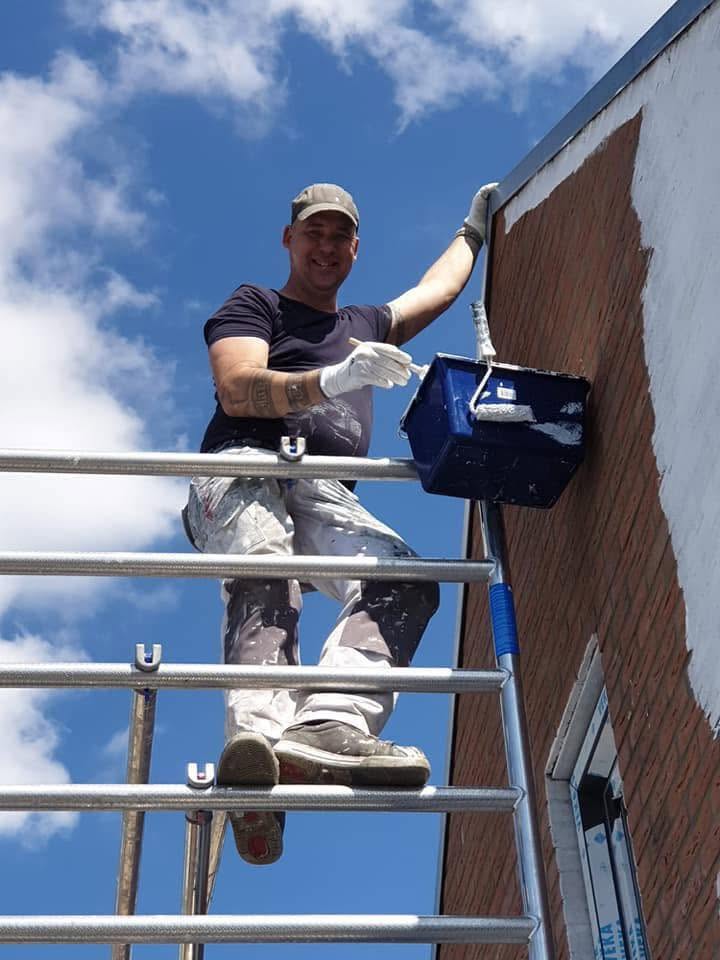 Schilder Vergeest aan het werk op een steiger bij een gevel
